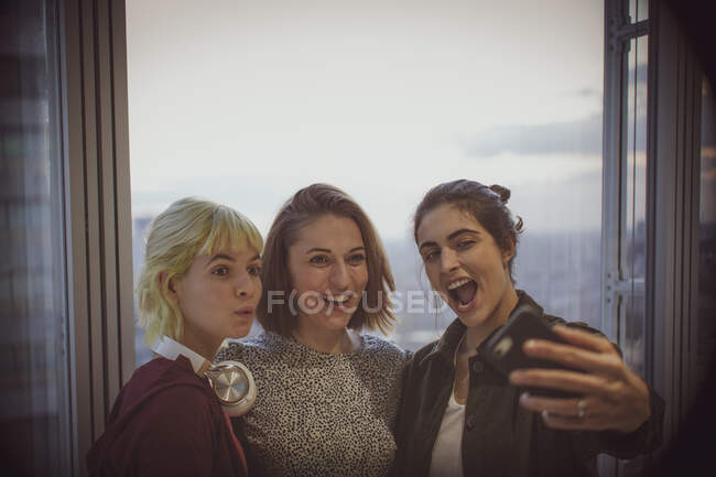Empresárias felizes tirando selfie na janela do escritório — Fotografia de Stock