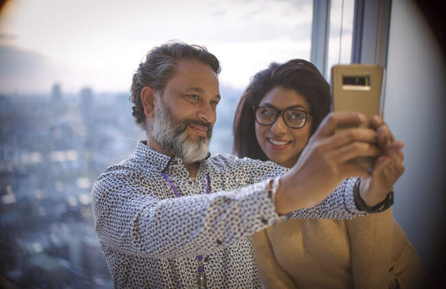 Empresários tirando selfie na janela do escritório highrise — Fotografia de Stock