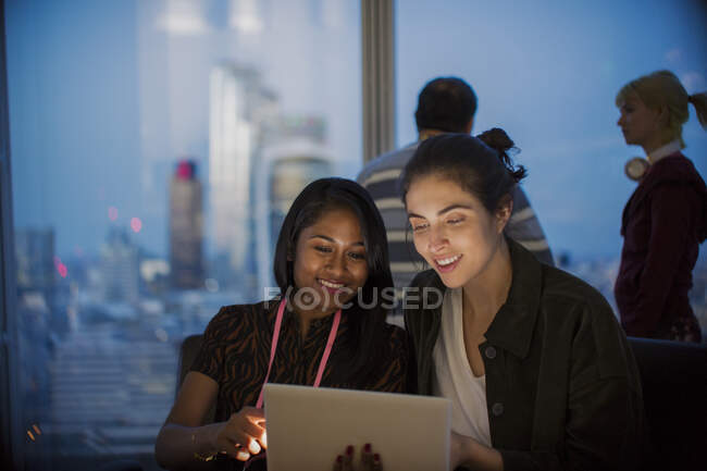 Donne d'affari sorridenti con tablet digitale che lavorano fino a tardi in ufficio — Foto stock