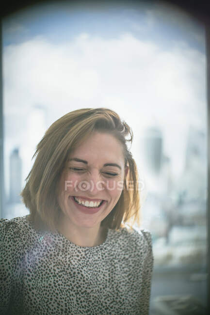Feliz mujer de negocios riendo en la ventana - foto de stock