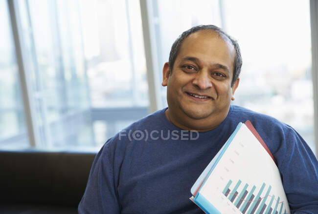 Portrait confident businessman with paperwork in office — Stock Photo