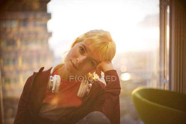 Porträt kreative junge Geschäftsfrau mit Kopfhörern am Bürofenster — Stockfoto