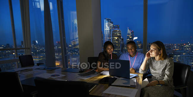 Les gens d'affaires travaillant tard à l'ordinateur portable dans la salle de conférence Highrise — Photo de stock