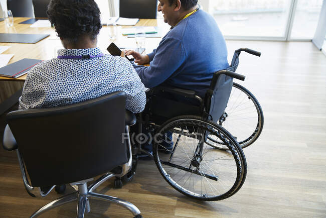 Homme d'affaires en fauteuil roulant utilisant le téléphone intelligent dans la salle de conférence réunion — Photo de stock