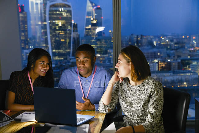 Business people working late at laptop in urban highrise office — Stock Photo