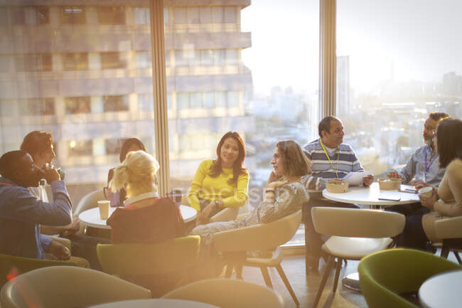 Business people talking and eating lunch in highrise cafeteria — Stock Photo