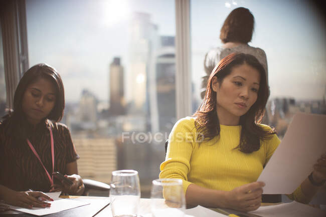 Ділові жінки оглядають документи у високогірній конференц-залі зустрічі — стокове фото