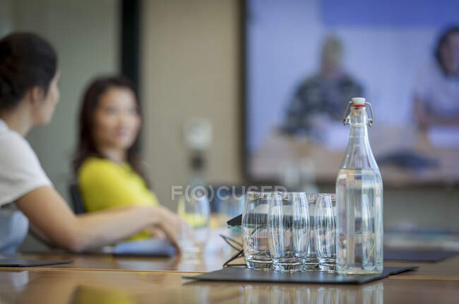 Botella de agua y vasos en la mesa de conferencias - foto de stock