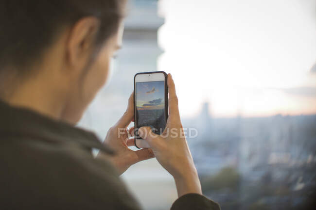 Femme avec appareil photo téléphone photographie coucher de soleil de highrise — Photo de stock