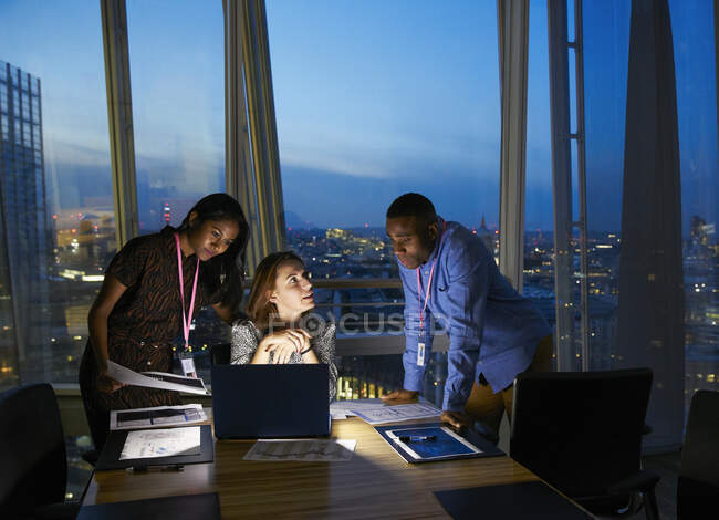 Business people working late at laptop in highrise conference room — Stock Photo