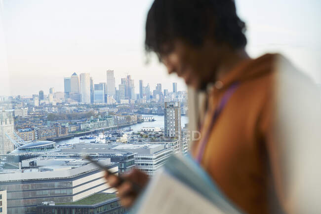 Businessman using smart phone at highrise window, London, UK — Stock Photo