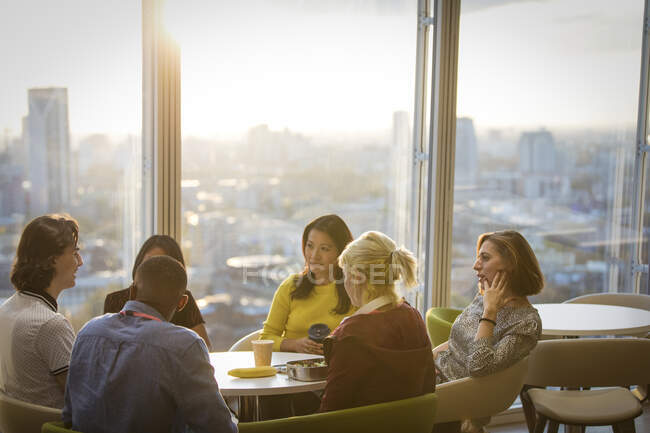 Geschäftsleute unterhalten sich in der Cafeteria eines sonnigen Hochhauses — Stockfoto
