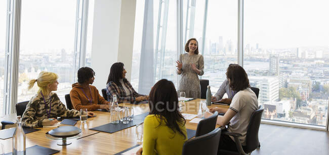 Mujer de negocios dirigiendo reunión de sala de conferencias en oficina de rascacielos - foto de stock