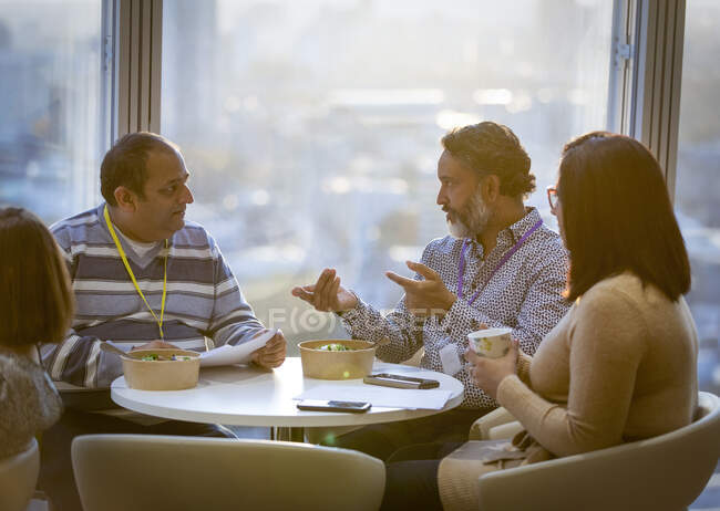 Business people talking and eating lunch in office cafeteria — Stock Photo