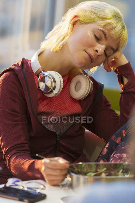 Tired young female college closing eyes at lunch — Stock Photo