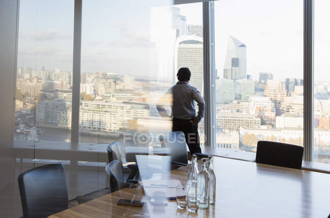 Pensativo hombre de negocios en la ventana de la oficina de rascacielos, Londres, Reino Unido - foto de stock