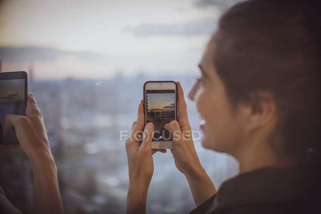 Empresária com câmera telefone fotografar pôr do sol na janela — Fotografia de Stock