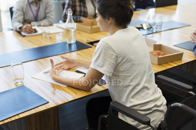 Femme d'affaires en fauteuil roulant discutant de la paperasserie en réunion — Photo de stock