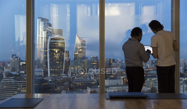 Businessmen working late at highrise office window, London, UK — Stock Photo