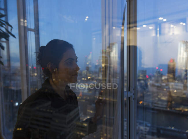 Thoughtful business woman working late at highrise office window — Stock Photo