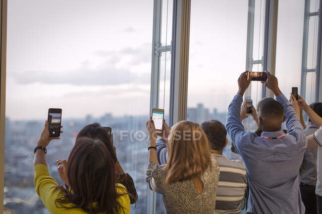 Business people with camera phones photographing city — Stock Photo