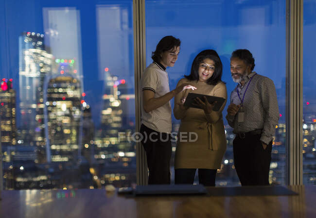 Empresários com tablet digital trabalhando até tarde na janela, Londres, Reino Unido — Fotografia de Stock