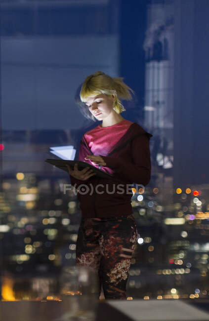 Jovem empresária com tablet digital trabalhando até tarde na janela do escritório — Fotografia de Stock