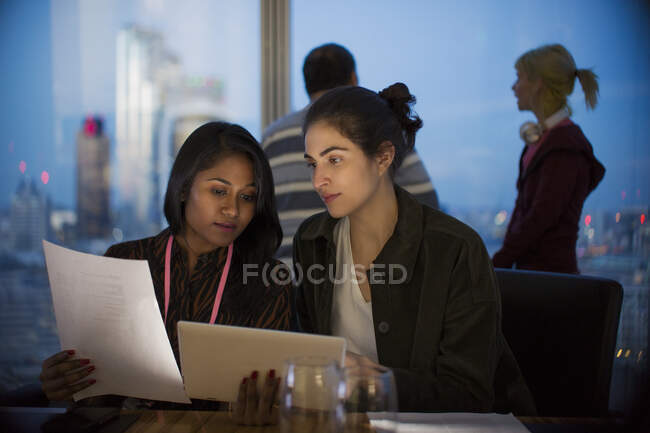 Empresárias com tablet digital trabalhando até tarde no escritório — Fotografia de Stock