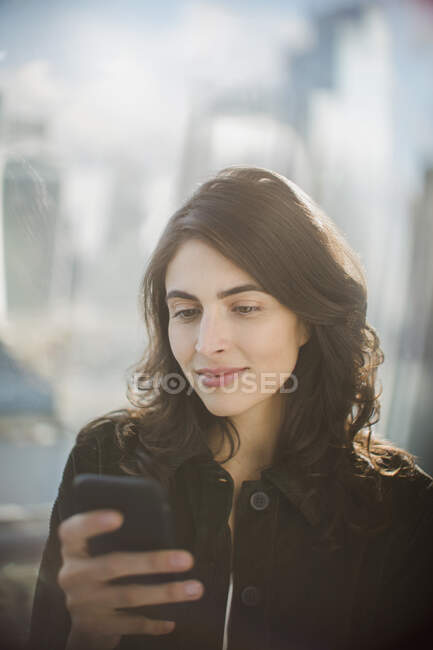 Donna d'affari che utilizza lo smart phone alla finestra — Foto stock