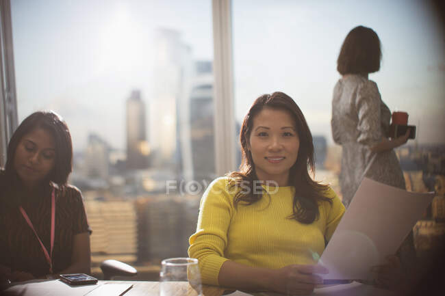 Retrato empresária confiante com papelada em reunião de sala de conferência — Fotografia de Stock