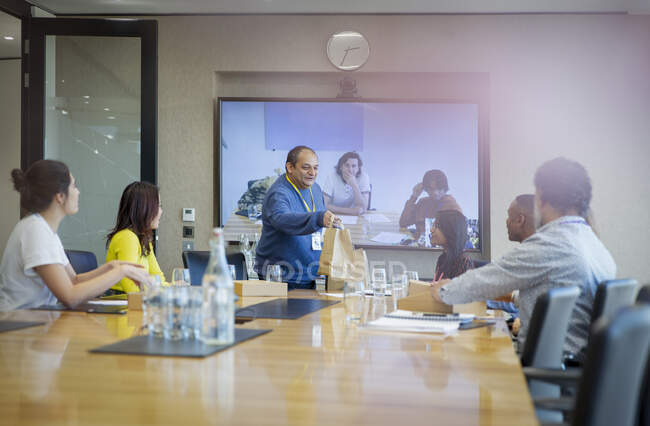 Empresário entrega almoço a colegas em reunião de sala de conferências — Fotografia de Stock