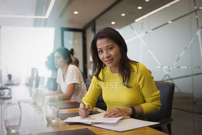 Ritratto donna d'affari sorridente con scartoffie in sala riunioni — Foto stock