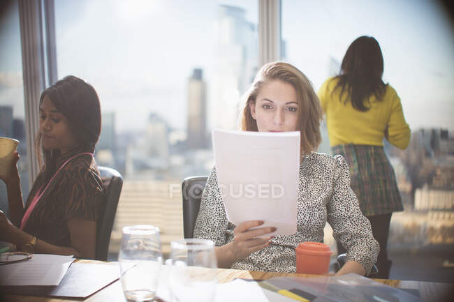 Empresária lendo papelada em reunião de sala de conferência — Fotografia de Stock