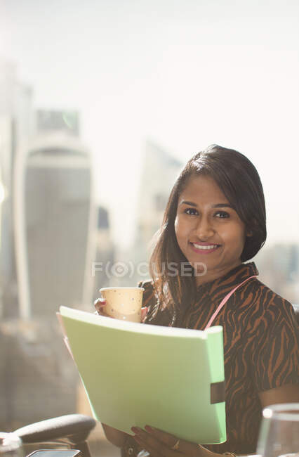 Retrato mulher de negócios feliz com papelada na janela do escritório ensolarado — Fotografia de Stock
