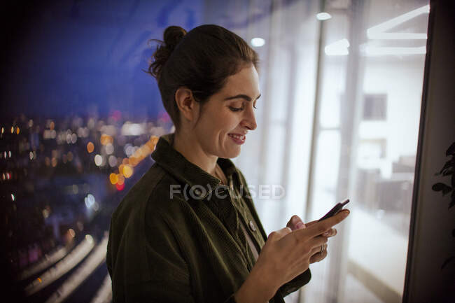 Деловая женщина, использующая смартфон в офисе ночью — стоковое фото