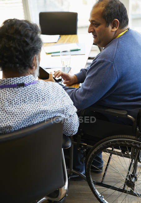 Бізнесмен в інвалідному візку розмовляє з колегою на зустрічі — стокове фото