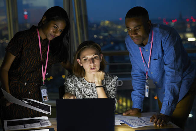Gente de negocios trabajando hasta tarde en el ordenador portátil en la oficina - foto de stock