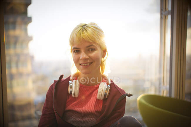 Portrait confident young woman with headphones at window — Stock Photo