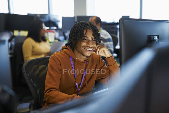 Homem de negócios sorrindo trabalhando no computador no escritório — Fotografia de Stock