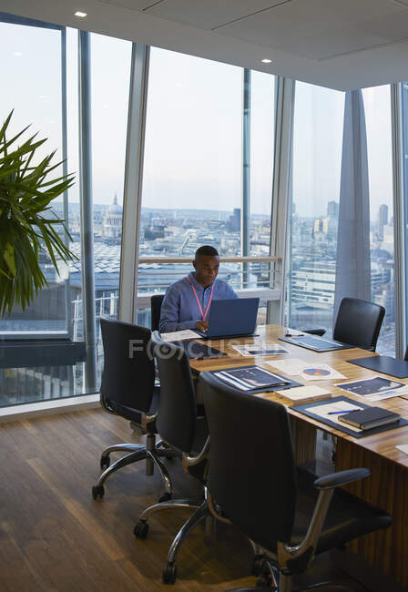 Businessman working at laptop in highrise conference room — Stock Photo