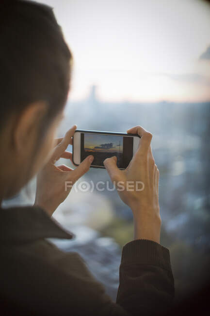 Женщина с фотоаппаратом фотографирует восход солнца над городом — стоковое фото