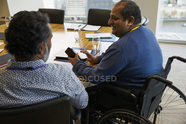 Бизнесмен в инвалидной коляске беседует с коллегой на встрече — стоковое фото