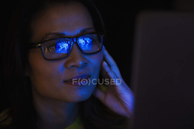 Close up laptop reflection in eyeglasses of businesswoman working late — Stock Photo