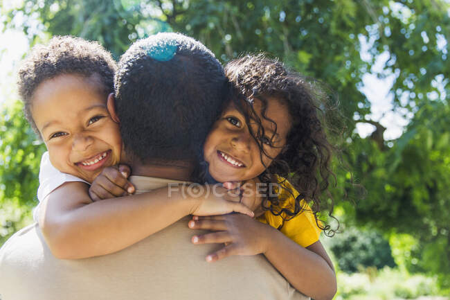 Happy daughter and son hugging father in sunny park — Stock Photo