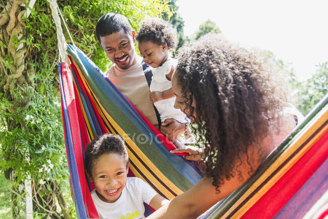 Retrato familia feliz en hamaca soleada del verano - foto de stock