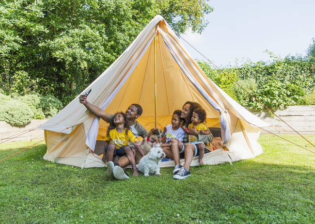 Счастливая семья делает селфи в палатке на заднем дворе — стоковое фото