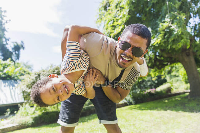 Retrato brincalhão pai e filho no quintal ensolarado — Fotografia de Stock