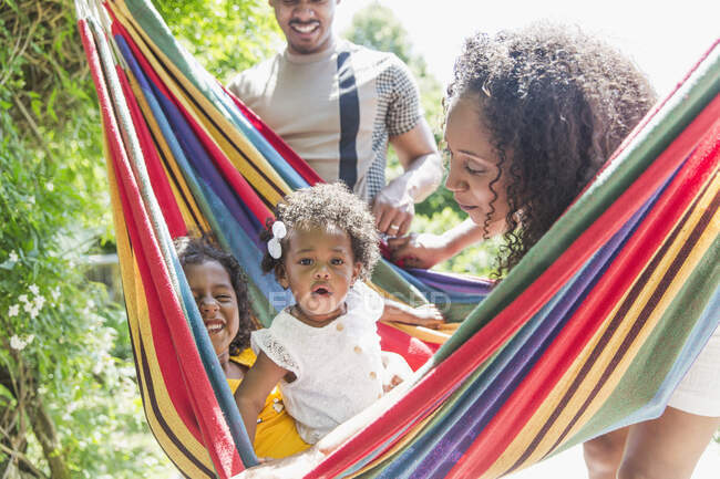 Portrait cute toddler girl in sunny summer hammock with family — Stock Photo