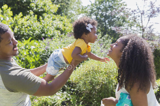 Affectionate parents and toddler daughter in sunny summer garden — Stock Photo