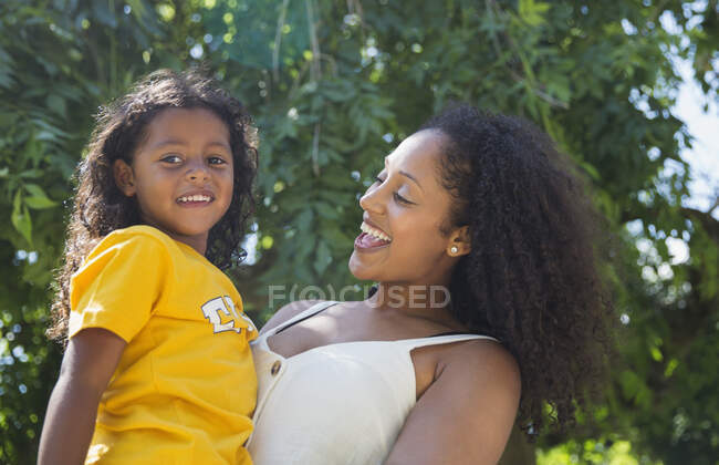 Portrait happy mother and daughter under tree in summer park — Stock Photo